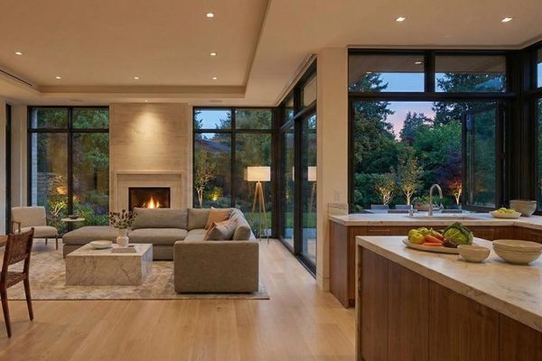 Modern open plan living room and kitchen with warm recessed lighting and large windows